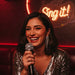 A women with brown hair and red lipstick singing karaoke